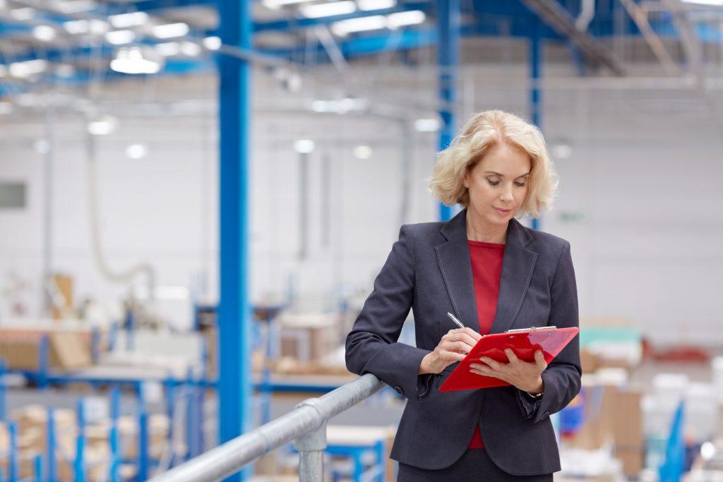 Senior businesswoman with clipboard in warehouse